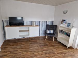 un soggiorno con TV e sedia di Wohnung Nordseebriese a Norden