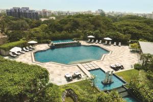 einen Blick über einen Pool mit Stühlen und Sonnenschirmen in der Unterkunft Hyatt Regency Chennai in Chennai