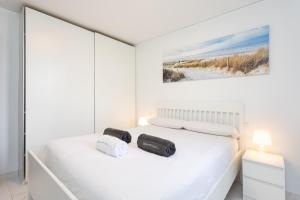 a white bedroom with a bed with two pillows at Nice apartment in the heart of Las Americas in Playa de las Americas