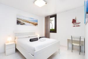 a white bedroom with a white bed and a chair at Nice apartment in the heart of Las Americas in Playa de las Americas