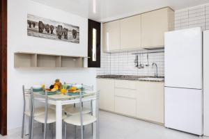 a kitchen with white cabinets and a table with fruit on it at Nice apartment in the heart of Las Americas in Playa de las Americas