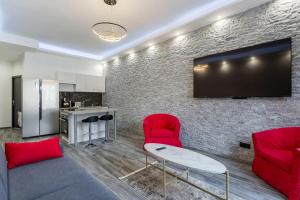 a living room with red chairs and a flat screen tv at Hamac Suites-Suite les Brotteaux in Lyon