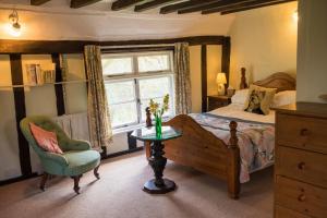 a bedroom with a bed and a chair and a window at Toad Hall in Swilland