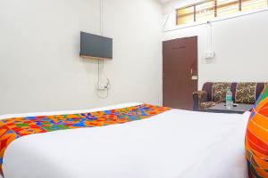 a room with a bed with a colorful blanket on it at FabHotel Om Sai in Nashik