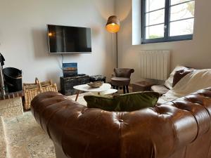 a living room with a brown leather couch and a table at Le Pressoir de Cheverny~Château~Golf~ in Cheverny