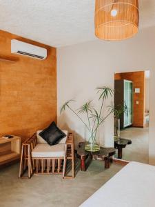 um quarto com uma cama, uma cadeira e uma planta em Villa Pantai Milagres Exclusive Hotel em São Miguel dos Milagres
