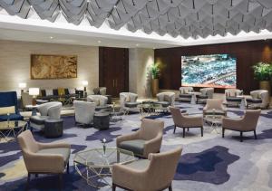 a lobby with chairs and tables and a projection screen at Movenpick Makkah Hajar Tower in Makkah