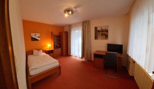 a bedroom with a bed and a desk with a television at Pension Wortmann in Bad Laer