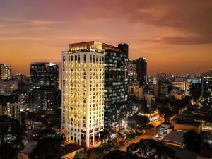 a tall white building in a city at night at Hotel Des Arts Saigon Mgallery Collection in Ho Chi Minh City