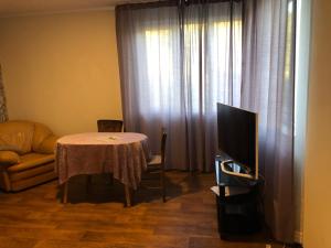 Una sala de estar con una mesa y un televisor. en Rose garden, en Batovo