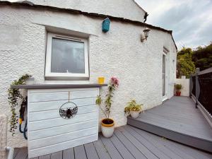 a white building with a window and a wooden deck at Clover Neuk Mews Cottage, 34a Main Road in Fairlie