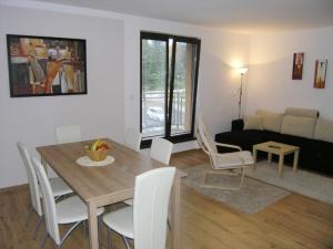 a living room with a wooden table and white chairs at Ernesta Club Lipno in Lipno nad Vltavou