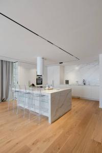 a white kitchen with a counter and chairs in it at Luxury House at Xanadu Residence in Ulaanbaatar
