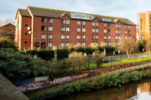 un edificio con graffiti en él junto a un río en Campanile Manchester, en Mánchester