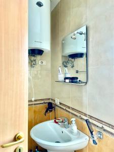 y baño con lavabo blanco y espejo. en Easy Peasy - 9th floor view downtown en Tirana