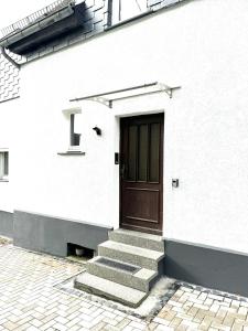 un edificio bianco con una porta marrone e scale di Ferienhaus Dierdorf a Dierdorf