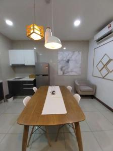 a kitchen with a wooden table with white chairs at KL Gateway Residency in Kuala Lumpur