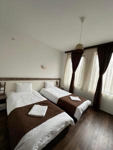 two beds in a hotel room with windows at Бялата Къща in Chakalarovo