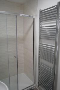 een douche met een glazen deur in de badkamer bij A1M Hampton Lakes Brand New Entire House in Peterborough