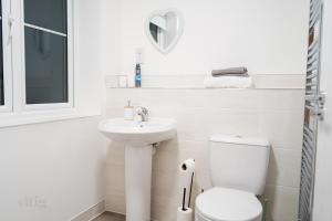 a white bathroom with a toilet and a sink at A1M Hampton Lakes Brand New Entire House in Peterborough