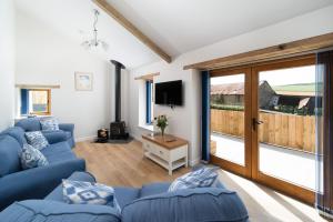 a living room with blue couches and a sliding glass door at The Old Piggery in Stoke Rivers