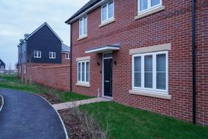 una casa de ladrillo rojo con puerta negra y entrada en A1M Hampton Lakes Brand New Entire House en Peterborough
