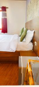 a bed with white sheets and green pillows at Calangute Beach Front in Calangute