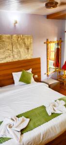 a bedroom with a bed with white sheets and green pillows at Calangute Beach Front in Calangute