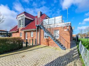 a brick house with a red roof and a staircase at Sonnendeck in Greetsiel