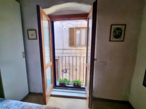 an open door to a balcony with two potted plants at Francigena Maison in Sutri