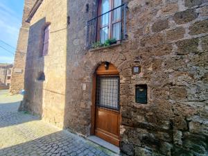 a stone building with a wooden door and a window at Francigena Maison in Sutri