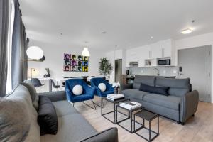 ein Wohnzimmer mit einem Sofa und zwei blauen Stühlen in der Unterkunft Liv MTL Downtown in Montreal
