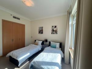 a bedroom with two beds and a window at Palm Jumeirah - Dubai 3 Bedroom Park Side - With Beach Access in Dubai