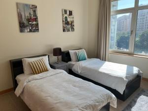 two beds in a room with a window at Palm Jumeirah - Dubai 3 Bedroom Park Side - With Beach Access in Dubai