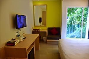 Habitación de hotel con cama, escritorio y TV. en Ocean and Ole Patong Hotel, en Patong Beach
