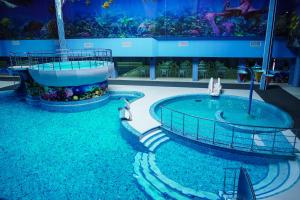 a large swimming pool in a building with a aquarium at Aquapark Hotel & Villas in Yerevan