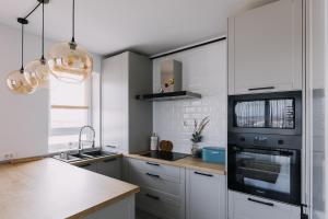 uma cozinha com armários brancos e um frigorífico preto em DreamHome Studio em Brasov