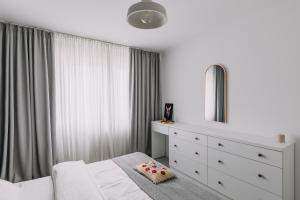 um quarto com uma cama branca, uma cómoda e um espelho em DreamHome Studio em Brasov