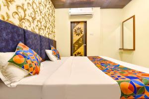 a bedroom with a large white bed with colorful pillows at FabHotel Spark in Jaipur