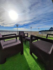 a group of benches sitting on top of the grass at Apartamentos La Toja in O Grove