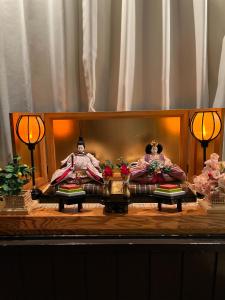 Dos muñecas están sentadas en un escenario en una habitación en Vegetarian House Jamoo, en Yamanakako