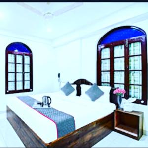 een slaapkamer met een bed, een wastafel en ramen bij Hotel Jheel Mahal New Town Inn West Bengal - Couple Friendly in Jojera