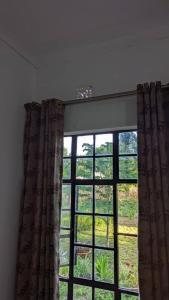 ventana en una habitación con cortina en Mwacha_Farm_house, en Moshi