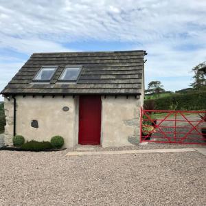 Mc Courts Barn, Tiny house in the Mournes في Hilltown: منزل صغير فيه باب احمر وسياج
