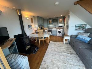 a living room with a couch and a table and a kitchen at Y Stabl in New Quay