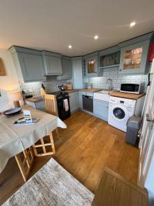 a kitchen with white appliances and a table in it at Y Stabl in New Quay