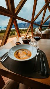 埃爾卡拉法特的住宿－Estancia Patagonia El Calafate - Pristine Luxury Camps，桌上的盘子,佐以一杯葡萄酒