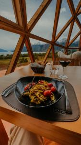 un plato de comida en una mesa con copas de vino en Estancia Patagonia El Calafate - Pristine Luxury Camps en El Calafate