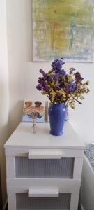 エリセイラにあるCasa da Avó Isaura - Ericeiraの白いテーブルの上に紫色の花を咲かせた青い花瓶