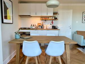 uma cozinha com uma mesa de madeira e cadeiras brancas em Designer 2 bedroom flat with office em Londres